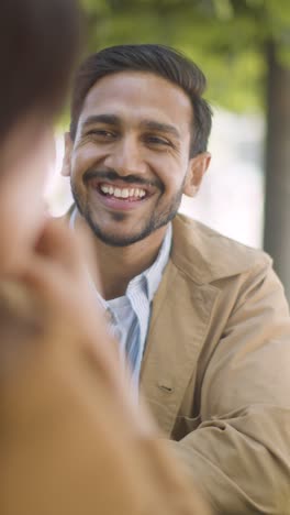 Vertical-Video-Close-Up-Of-Muslim-Couple-On-Date-Meeting-And-Talking-At-Table-On-City-Street-Together-3